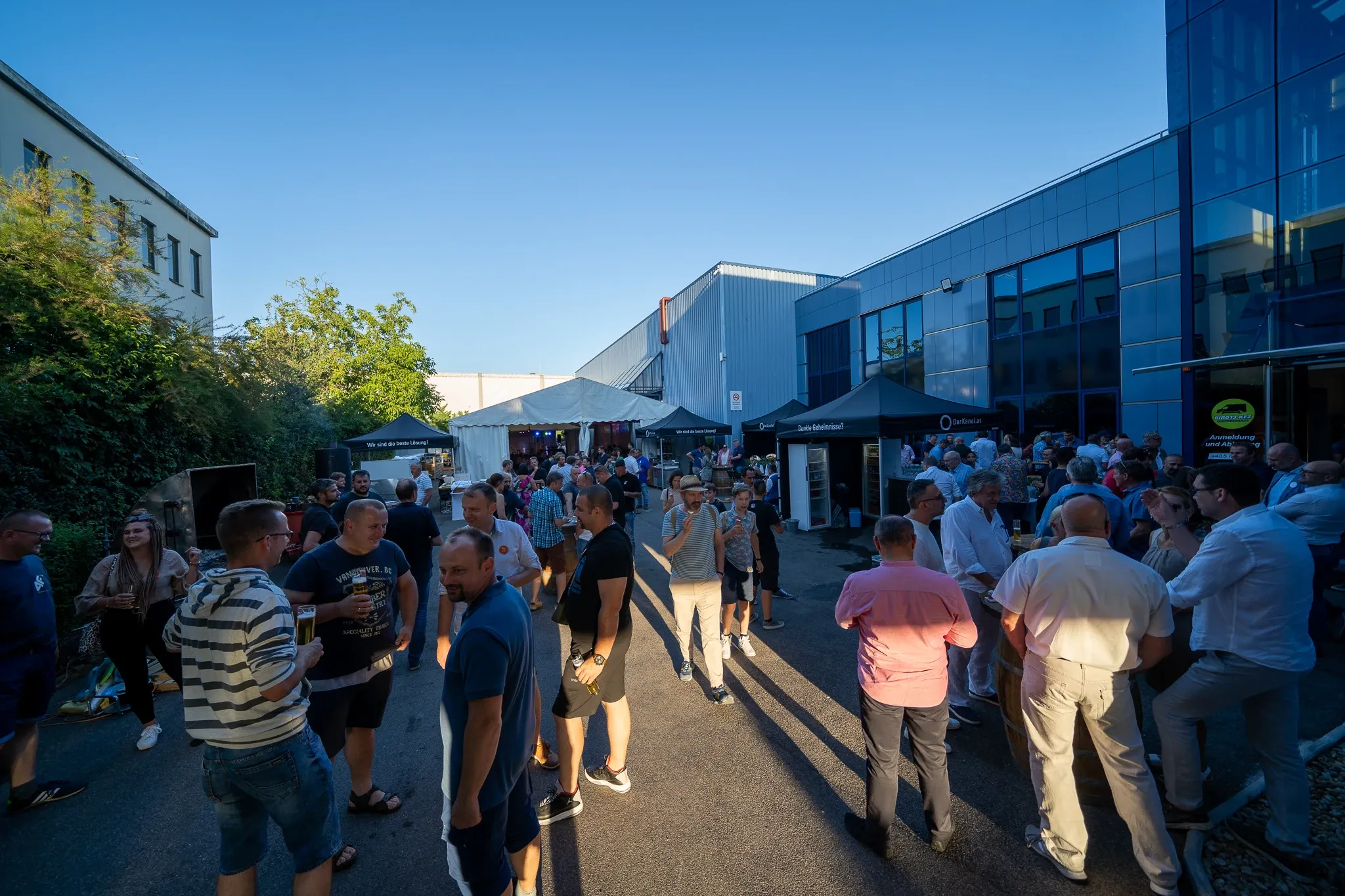 Gäste im Gespräch zwischen den Hallen bei Sonnenschein