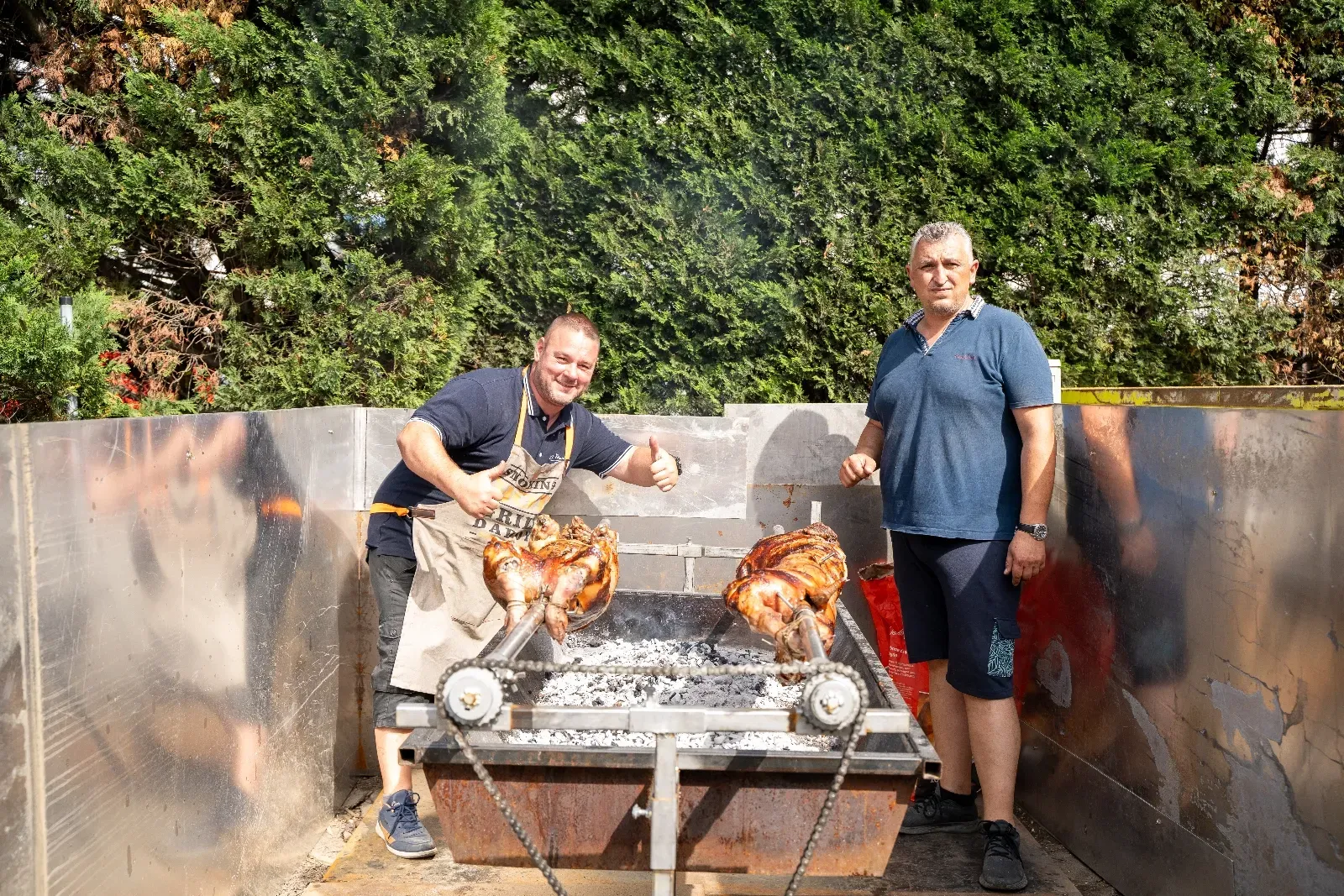 Zwei Griller am offenen Feuer mit zwei Spanferkeln am Spieß